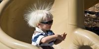 Static electricity from this plastic slide causes the child's hair to stand on end. The sliding motion stripped electrons away from the child's body, leaving an excess of positive charges, which repel each other along each strand of hair.